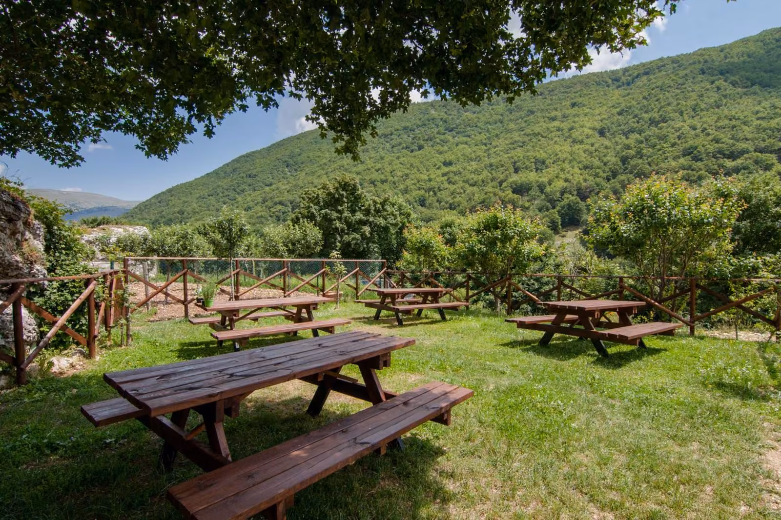 I tavoli da picnic sull'erba intorno all'agriturismo, con le montagne sullo sfondo